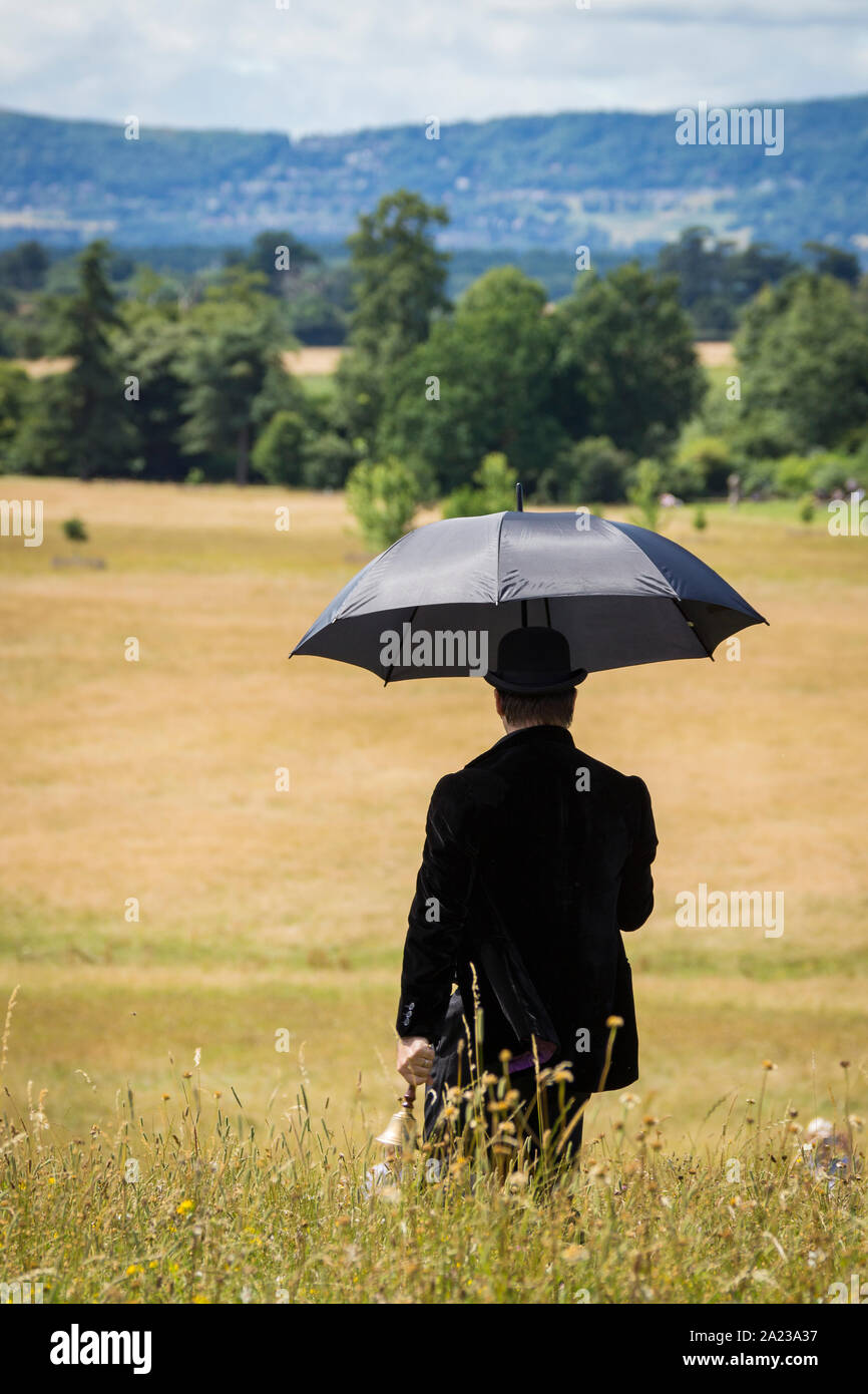 Uomo con ombrello e prendendo parte a un teatro all'aperto sembra di  produzione attraverso la campagna inglese in Worcestershire, Regno Unito  Foto stock - Alamy