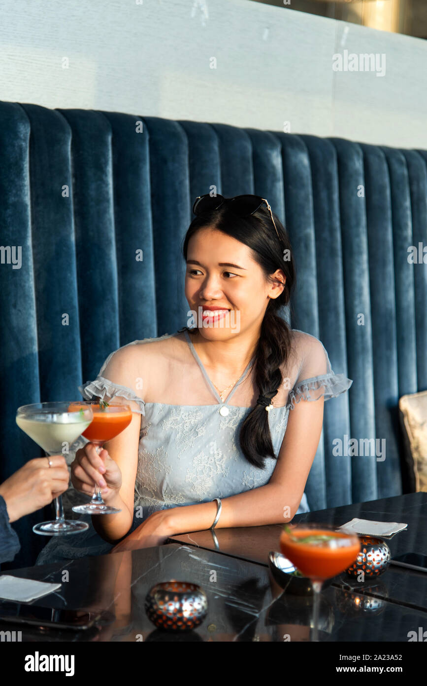 Asian Girls tostare con un cocktail presso il bar Foto Stock