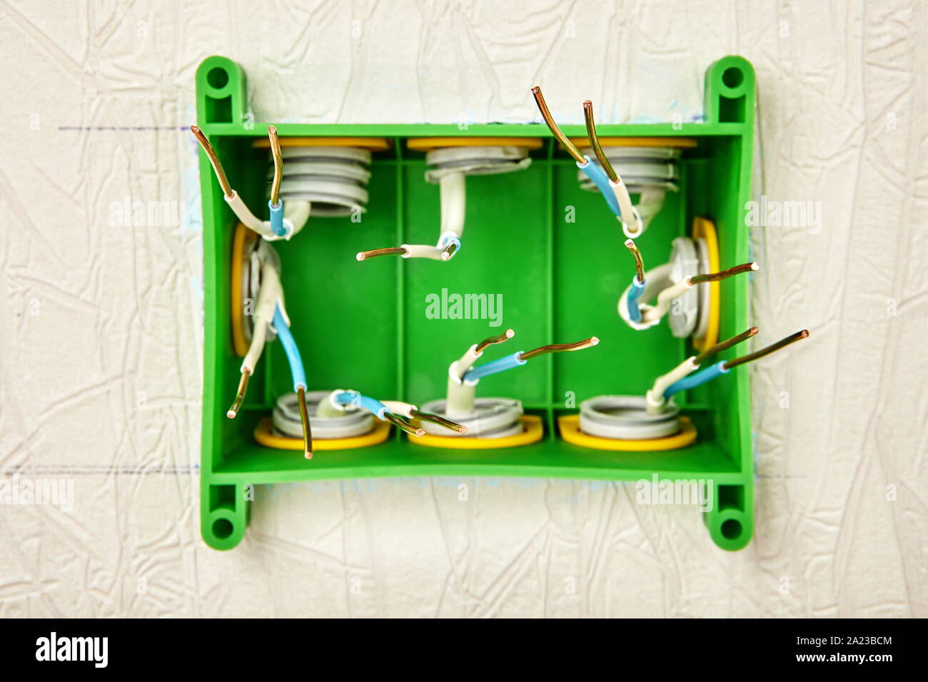 Installazione di un montato a parete cassetta di derivazione elettrica per il sistema elettrico domestico, quadrato verde in plastica scatola di distribuzione durante l'installazione, insu Foto Stock