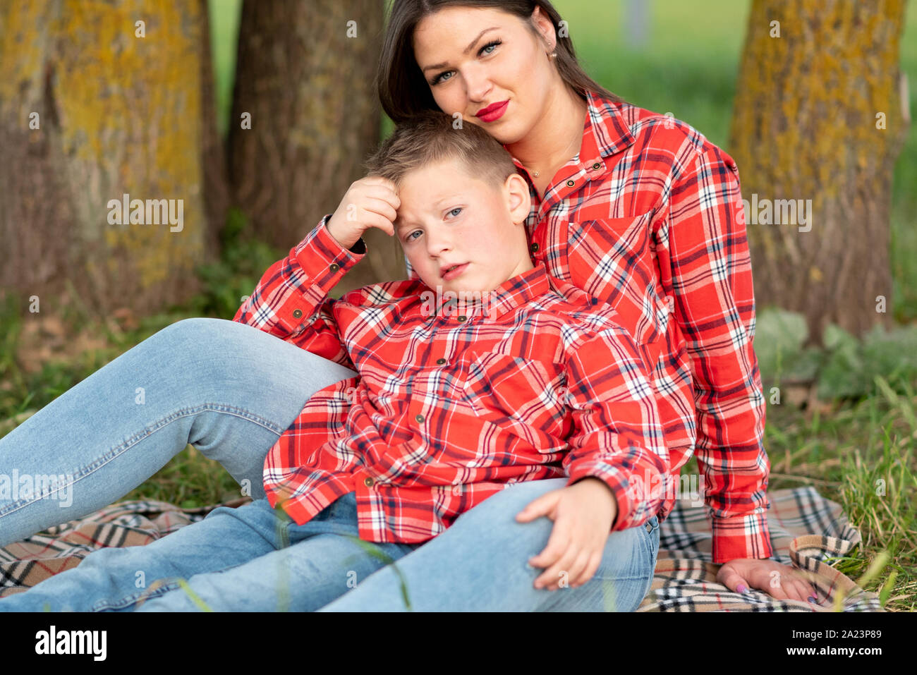 Madre e figlio seduti sul copriletto abbraccio delicatamente. Foto Stock