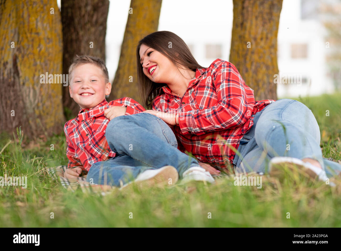 Madre e figlio, disteso sul loro lato sul copriletto, ridere allegramente. Foto Stock