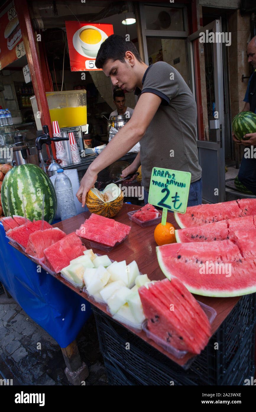 Un venditore il taglio delle fette di anguria in vendita presso la sua bancarella di strada di Istanbul Foto Stock