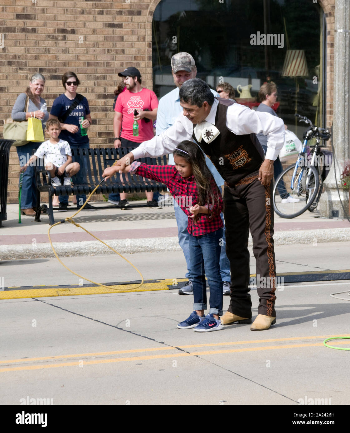 Javier Escamilla del balletto Folklorico Nacional insegna la filatura corda trucco per una giovane ragazza in due fiumi, Wisconsin etnico Fest street fair. Foto Stock