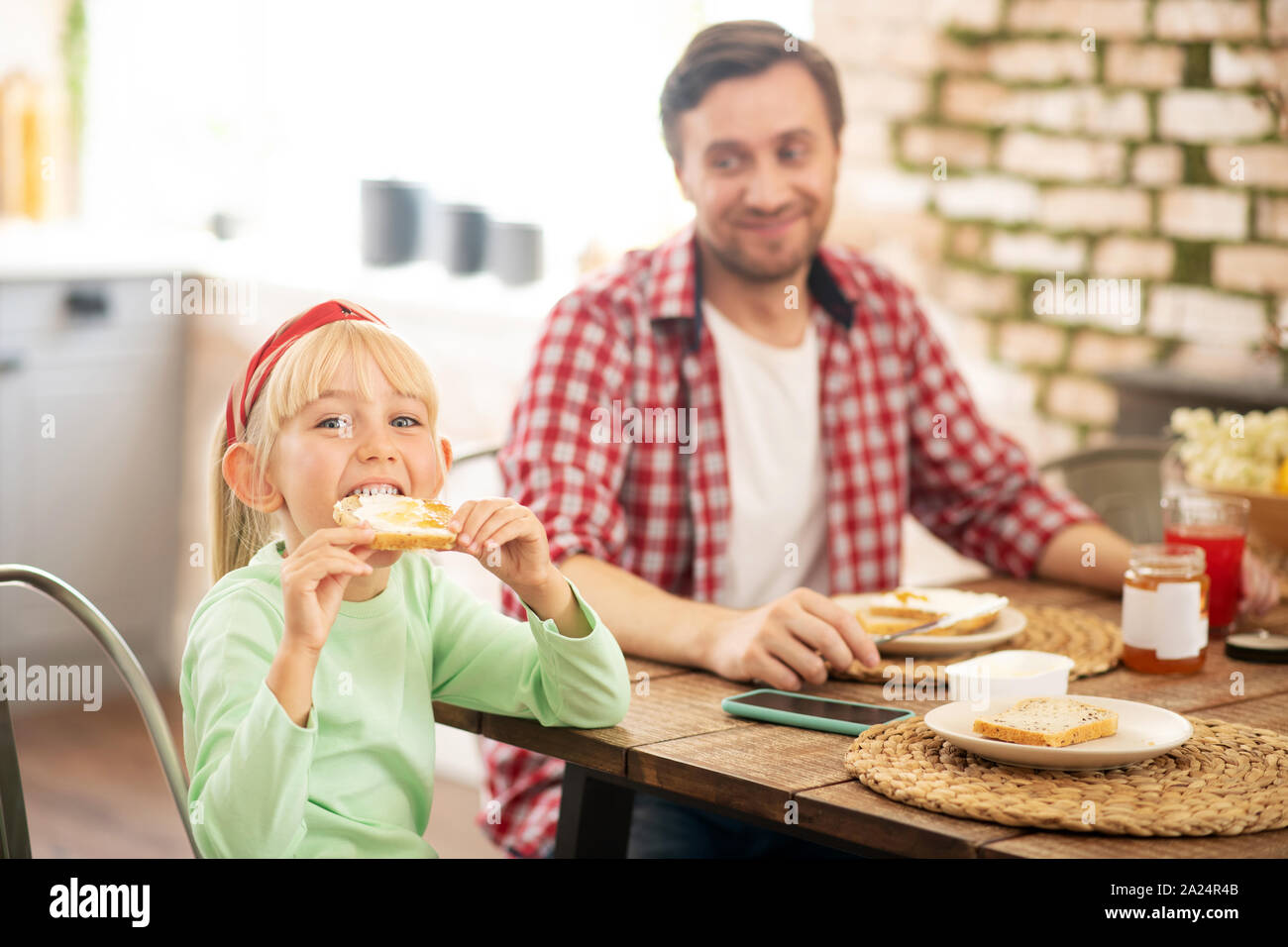 Funny Girl mordere toast mentre fate colazione con papà Foto Stock