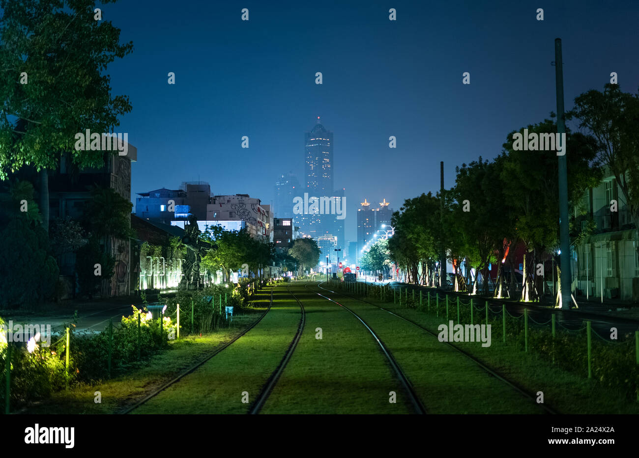 Kaohsiung, Taiwan: vista del verde gras coperto Kaohsiung Light Rail treno le vie che conducono verso la Tuntex Sky Tower 85 nel centro della città di notte. Foto Stock