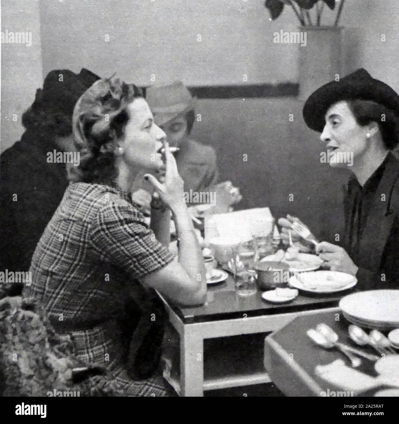 Due donne conversare e fumo durante un incontro a pranzo, Londra circa 1947 Foto Stock