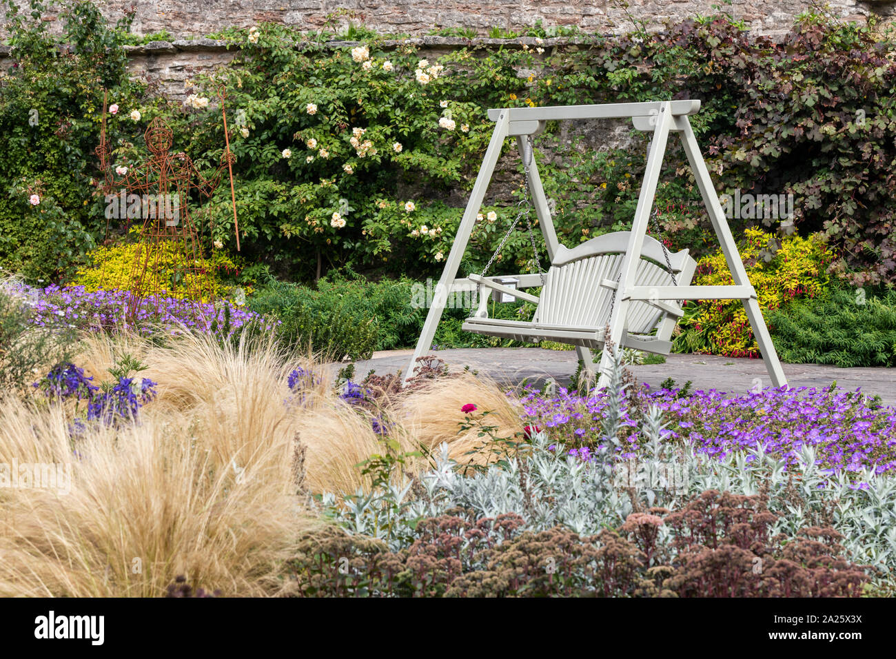 Un di legno verniciato banco oscillante nel bellissimo giardino del Palazzo dei Vescovi, pozzi, Somerset, Regno Unito Foto Stock