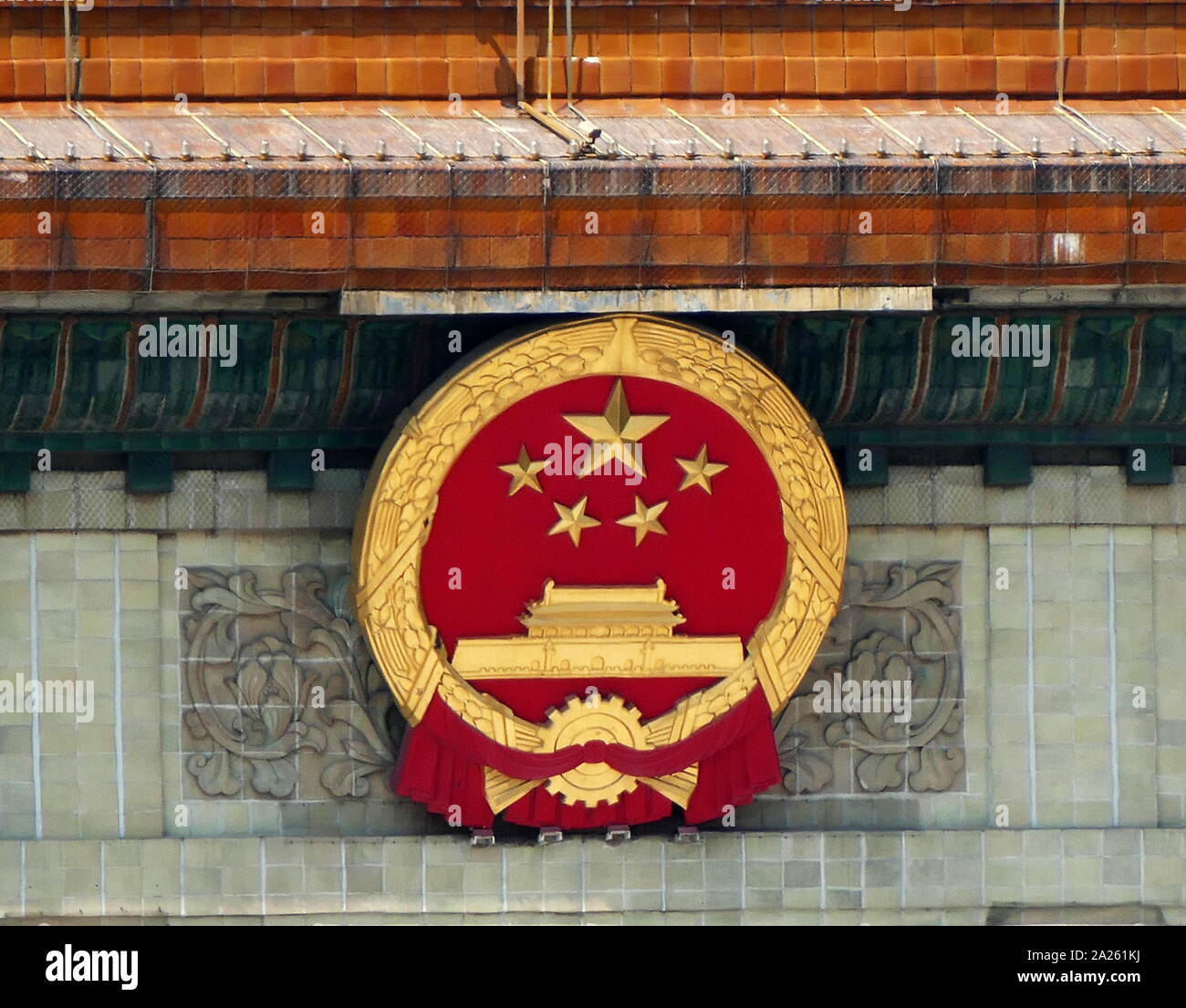 Lo Stato cinese emblema sopra l'entrata della Grande Sala del Popolo di Pechino, Cina. Il cinque stelle su l'emblema hanno lo stesso significato di quelle sulla bandiera nazionale. L'ingranaggio d'oro rappresenta i lavoratori. Il grano rappresenta i contadini. Il collegamento di questi rappresenta la alleanza Worker-Peasant guidato dalla classe operaia della Cina. Foto Stock