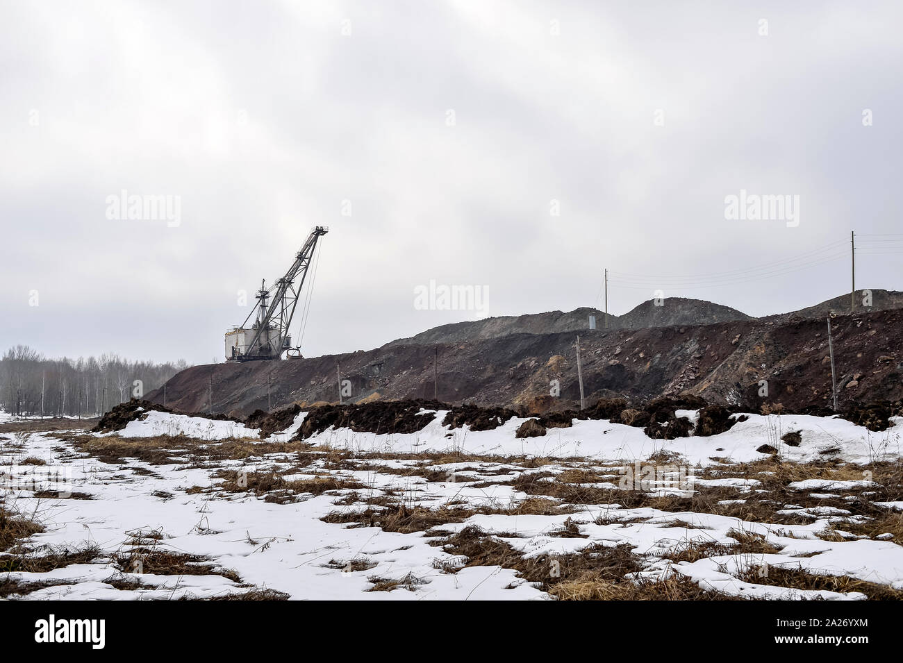 Pile di quarzite con un enorme escavatore a piedi e i resti della foresta in background. Copia dello spazio. Foto Stock