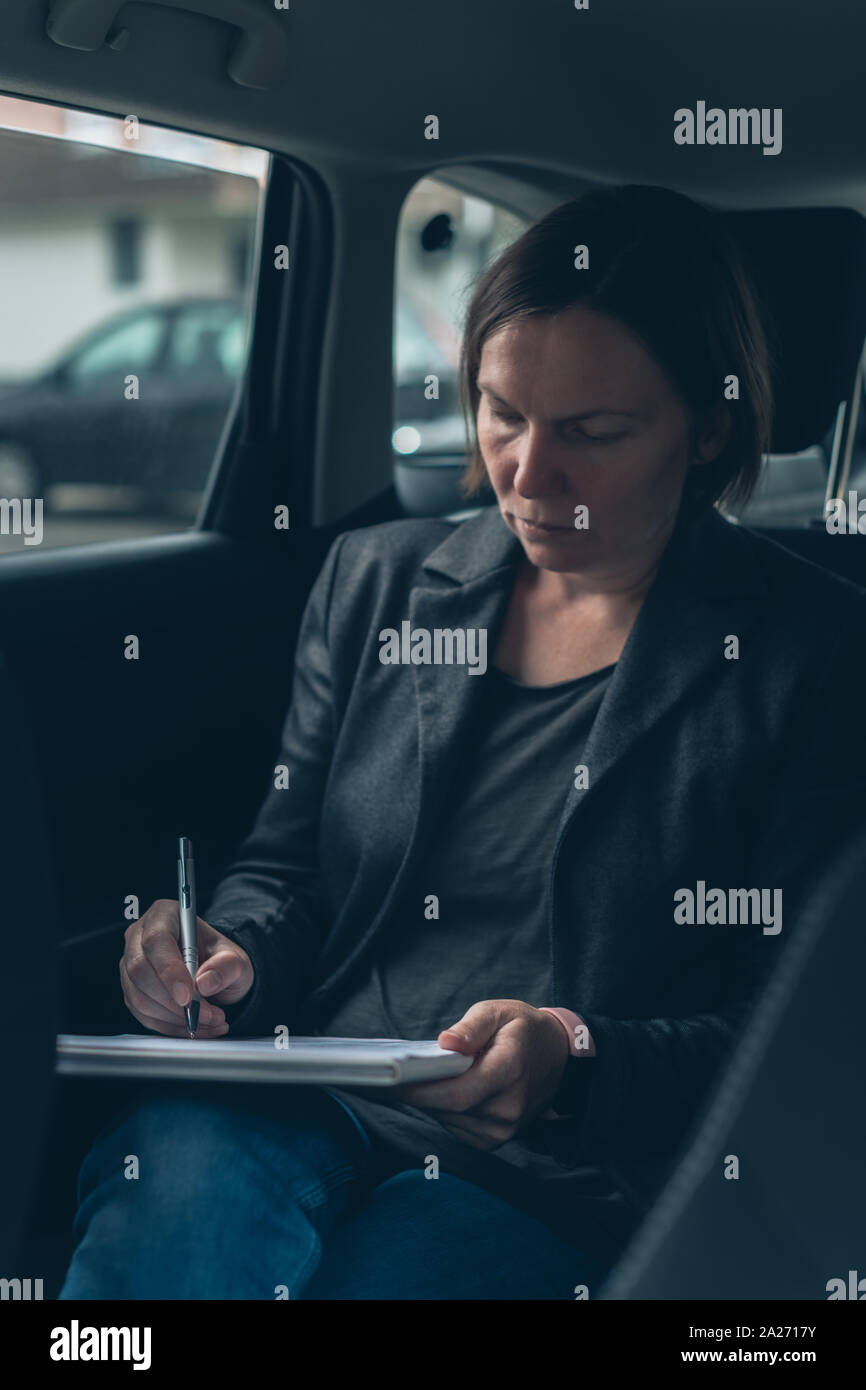 Imprenditrice facendo la documentazione e analisi di business report seduti in auto presso il sedile posteriore Foto Stock