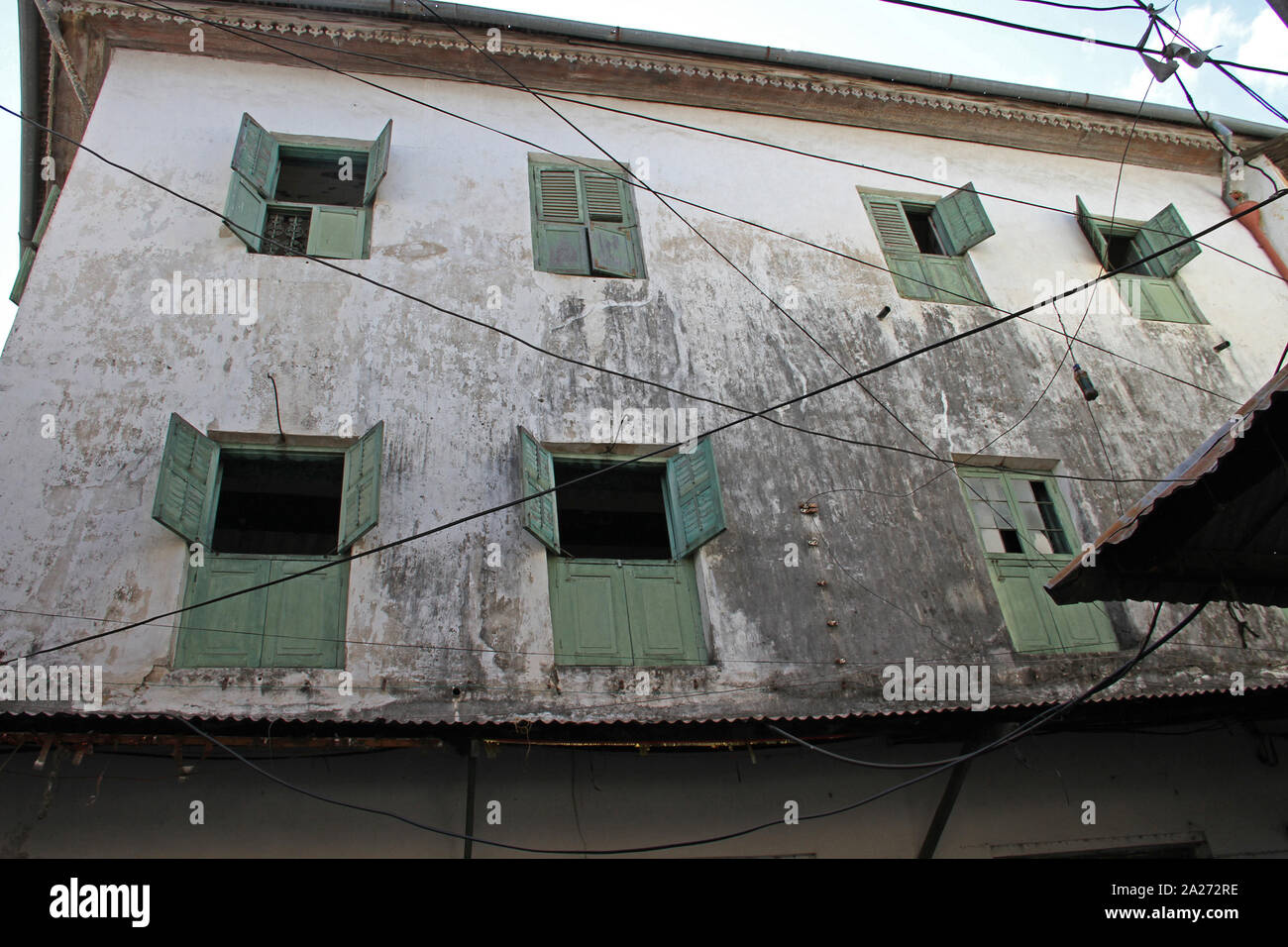 Usurati vicolo con schiena verde windows e persiane di Stone Town Zanzibar, isola di Unguja, Tanzania. Foto Stock