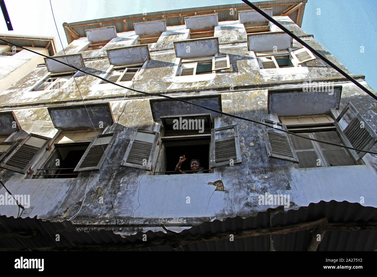 Appartamento locali blocco di appartamenti edificio e kid a finestra, Stone Town, Zanzinbar, isola di Unguja, Tanzania. Foto Stock