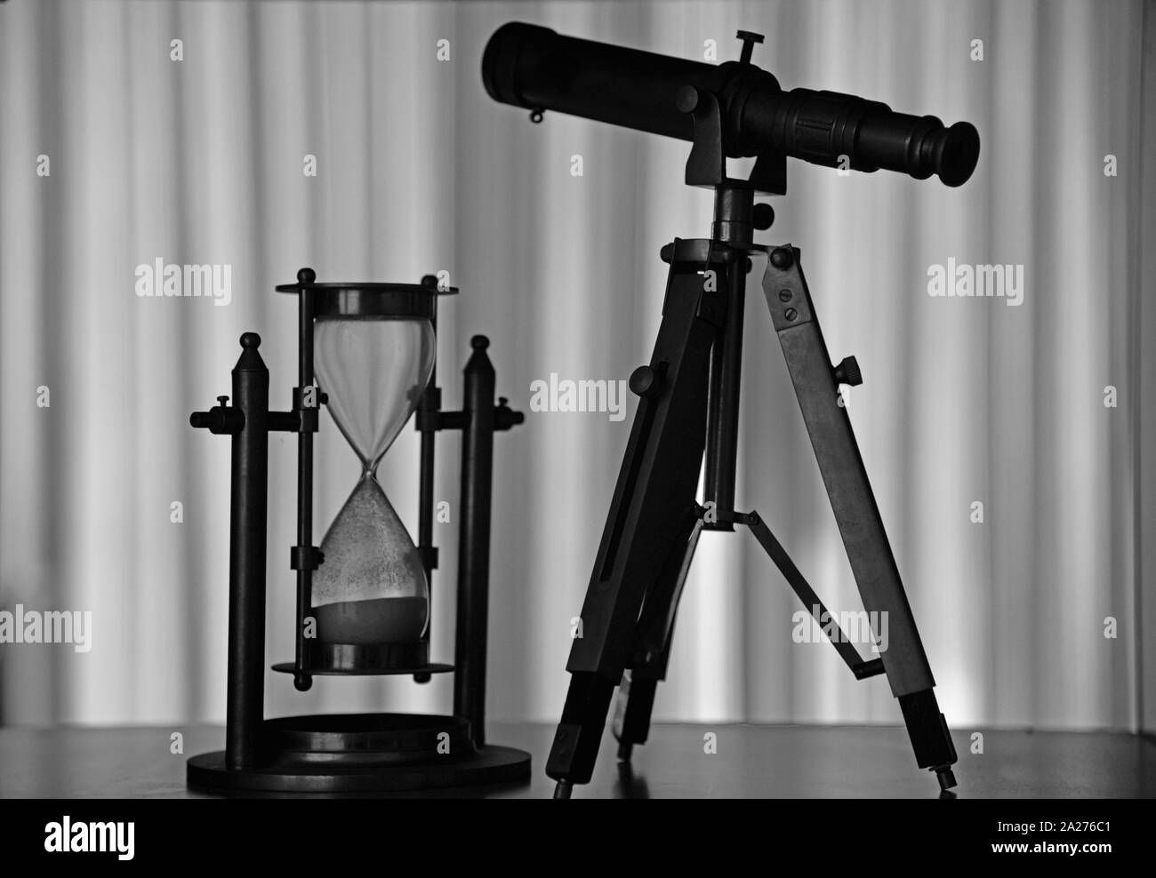 Sagome di una clessidra ed un telescopio su un ripiano libreria. Concetto : tecnologia, esplorazione, scienza, osservazione, tempo, ecc. Foto Stock
