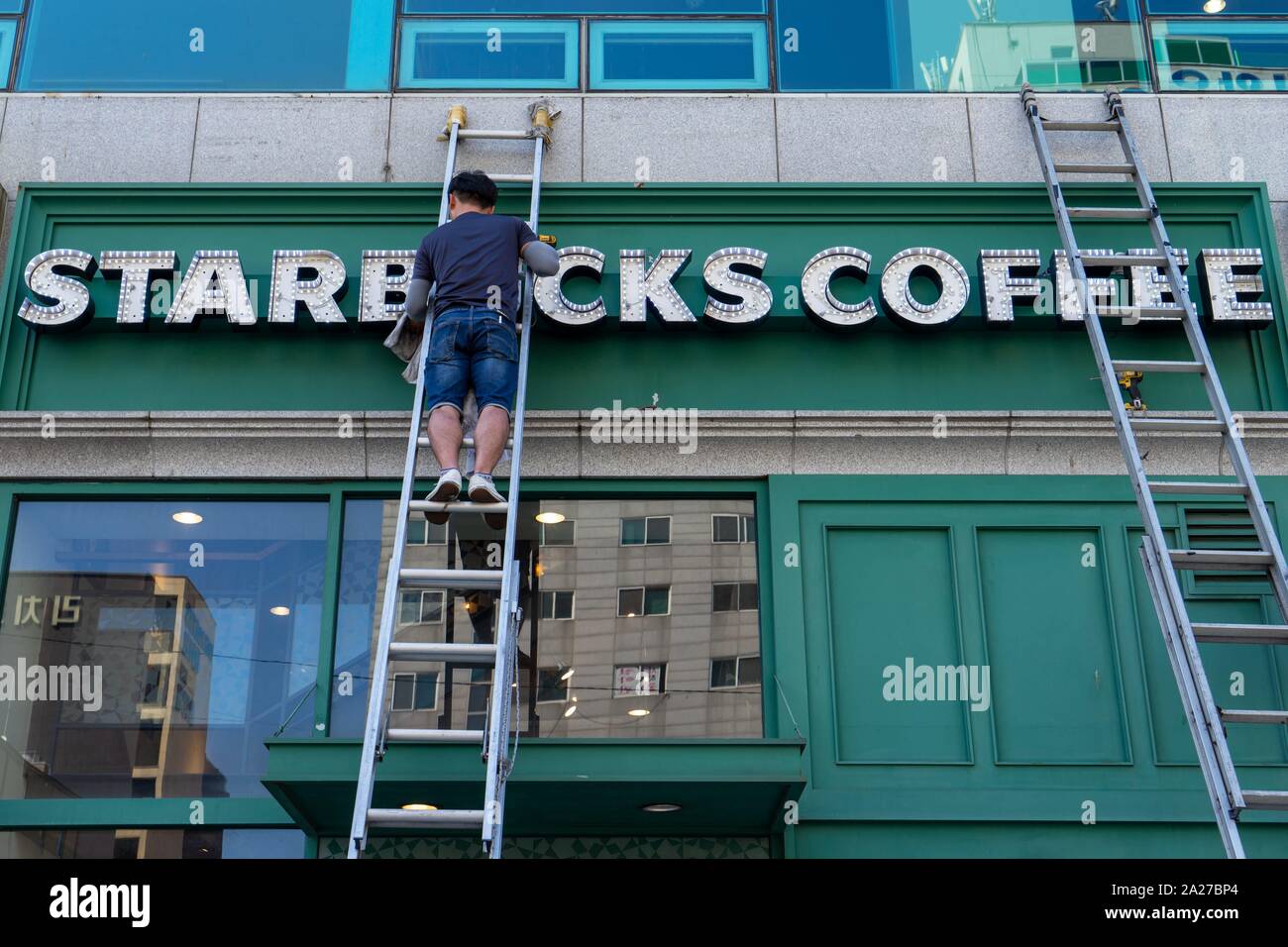 Corea del Sud: lavoratore pulisce Starbucks segno in corrispondenza di una posizione nel centro di Seul.Foto da 10. Settembre 2018. | Utilizzo di tutto il mondo Foto Stock