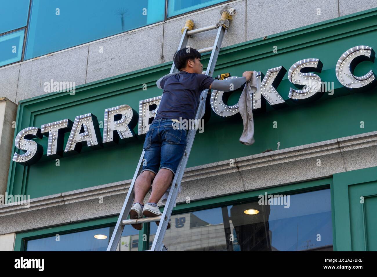 Corea del Sud: lavoratore pulisce Starbucks segno in corrispondenza di una posizione nel centro di Seul.Foto da 10. Settembre 2018. | Utilizzo di tutto il mondo Foto Stock