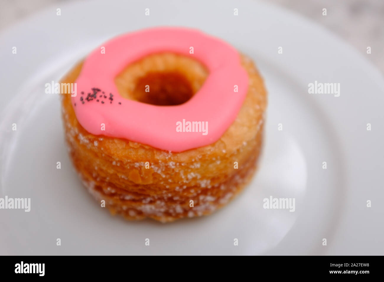 Una sola rosa cronut vetrato sfoglia su una piastra a Dominique Ansel Baker, Londra, Inghilterra Foto Stock