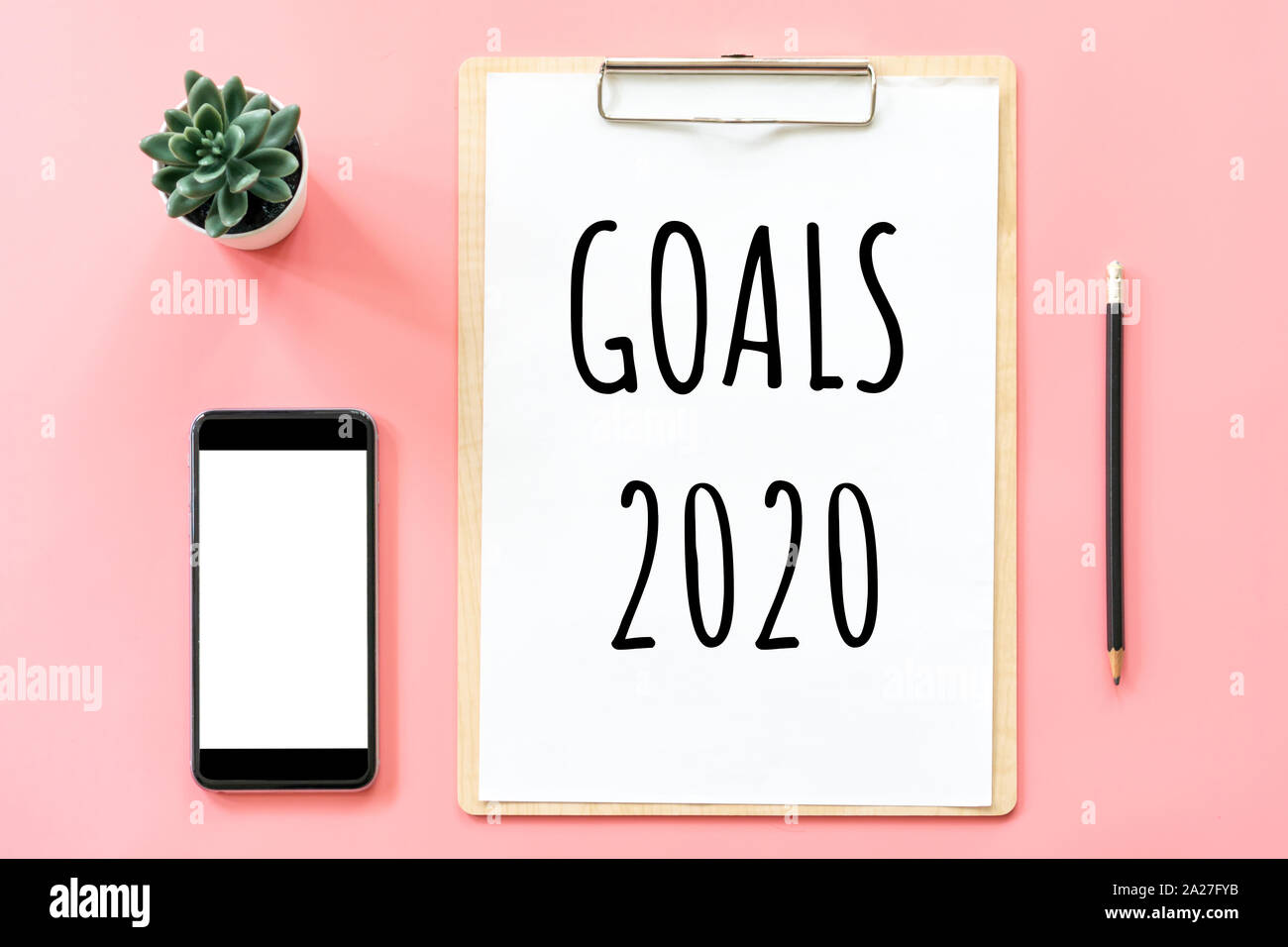 Anno nuovo concetto. Obiettivi 2020 e articoli di cartoleria, vuoto negli appunti, smartphone, pot impianto su pink color pastello con spazio di copia Foto Stock