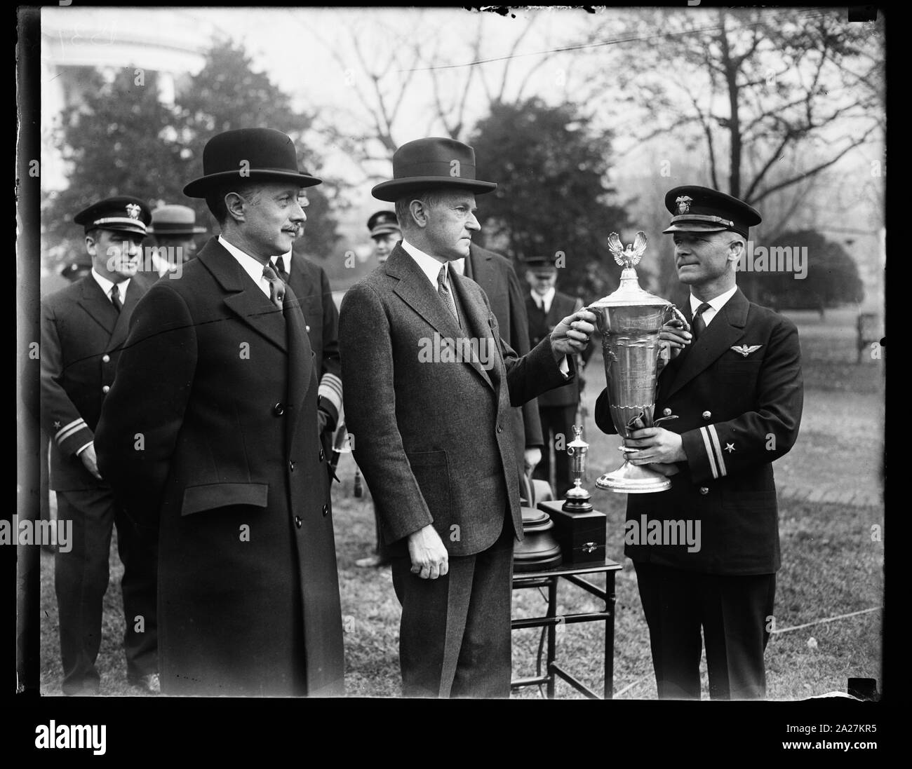 President Coolidge presenta Herbert Schiff Trophy per il crack Navy Flyer. Per eseguire la prodezza di mantenere il suo piano nell'aria per 1251 ore senza incidenti di qualsiasi natura durante l ultimo anno Lieut. James E. Dyer, crack U.S. Navy flyer, è stato presentato con l'Herbert Schiff Trophy by President Coolidge alla Casa Bianca di oggi. Il trofeo viene assegnato ogni anno a un pilota della Marina Militare sul merito di anno prestazioni in linea del dazio. William Schiff, fratello della riserva navale aviator in memoria di cui la coppa è dato, è mostrato sulla sinistra estrema Foto Stock