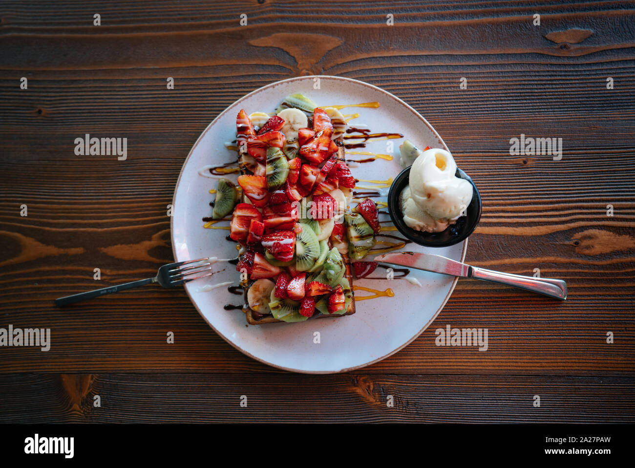 Gustosi e colorati i waffle belgi con fruites e cioccolato su un tavolo di legno. Foto Stock