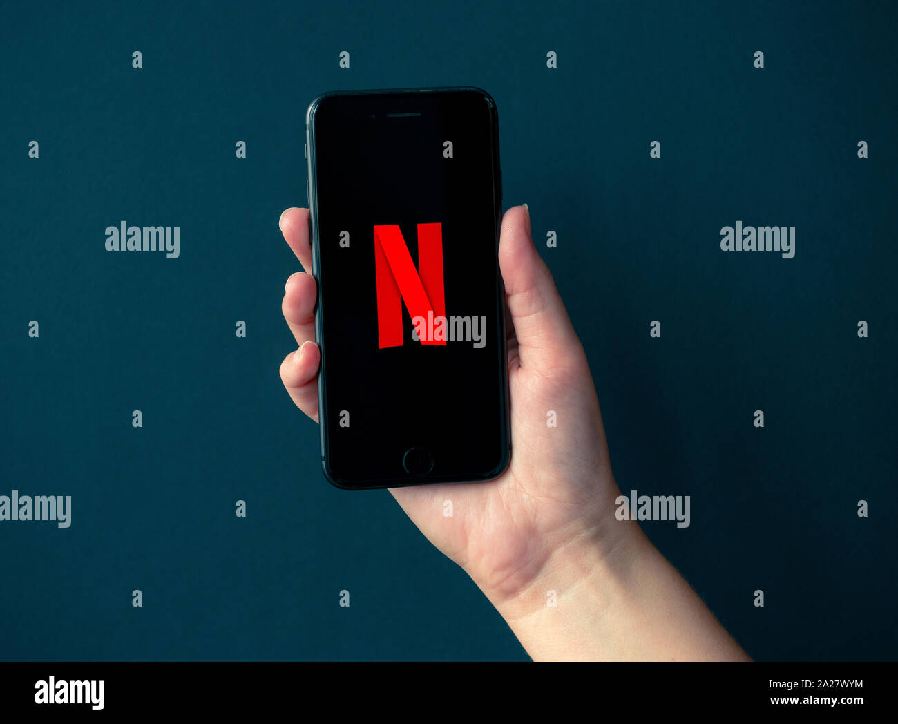 Kiev, Ucraina - 1 Ottobre 2019: Studio colpo di mano azienda Apple iPhone 8 con logotipo Netflix su uno schermo. Isolato su un nero lo sfondo della carta. Foto Stock