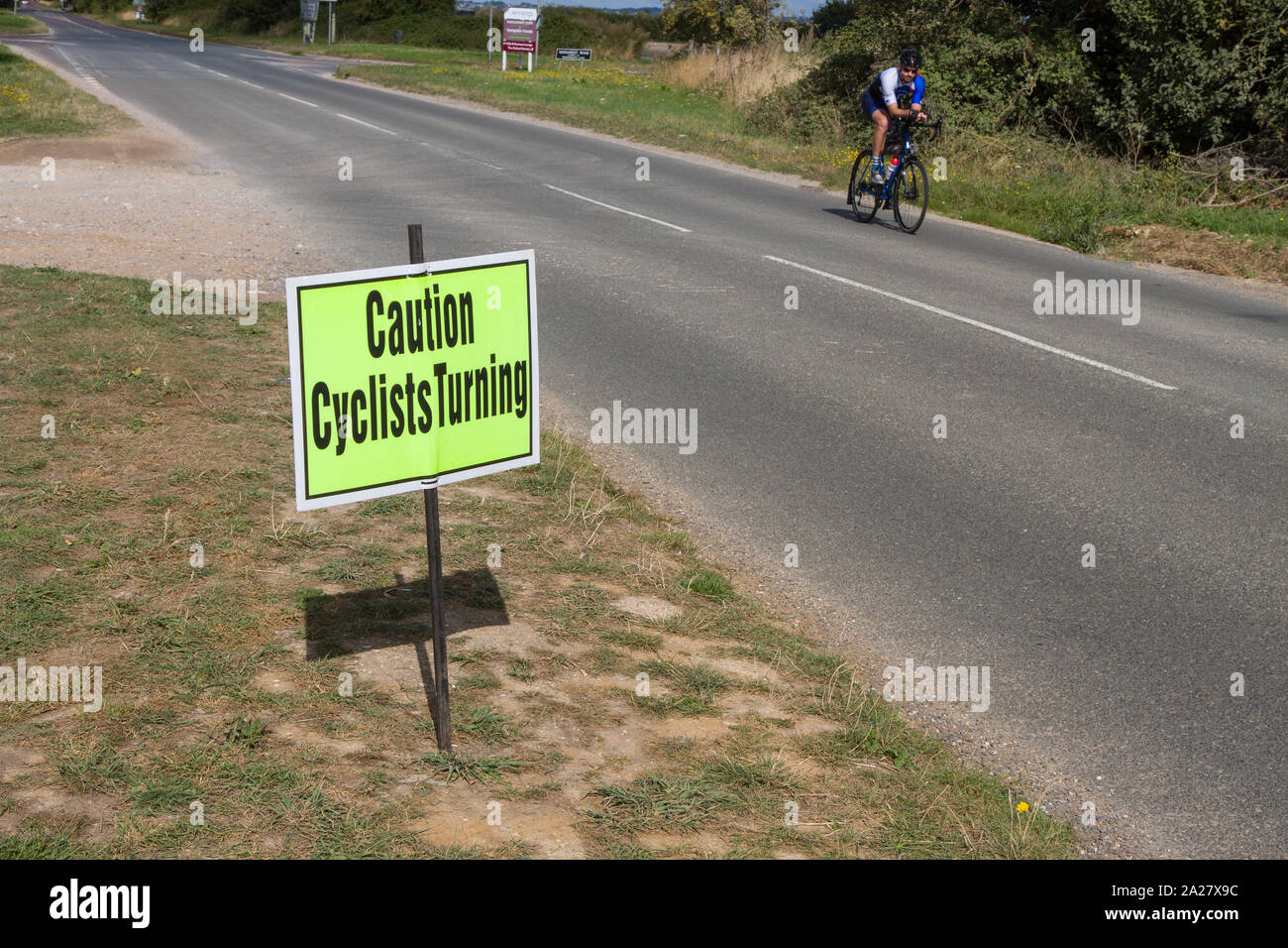 Un 'attenzione ai ciclisti la tornitura" sicurezza stradale segno di ciclismo su strada un orlo Foto Stock
