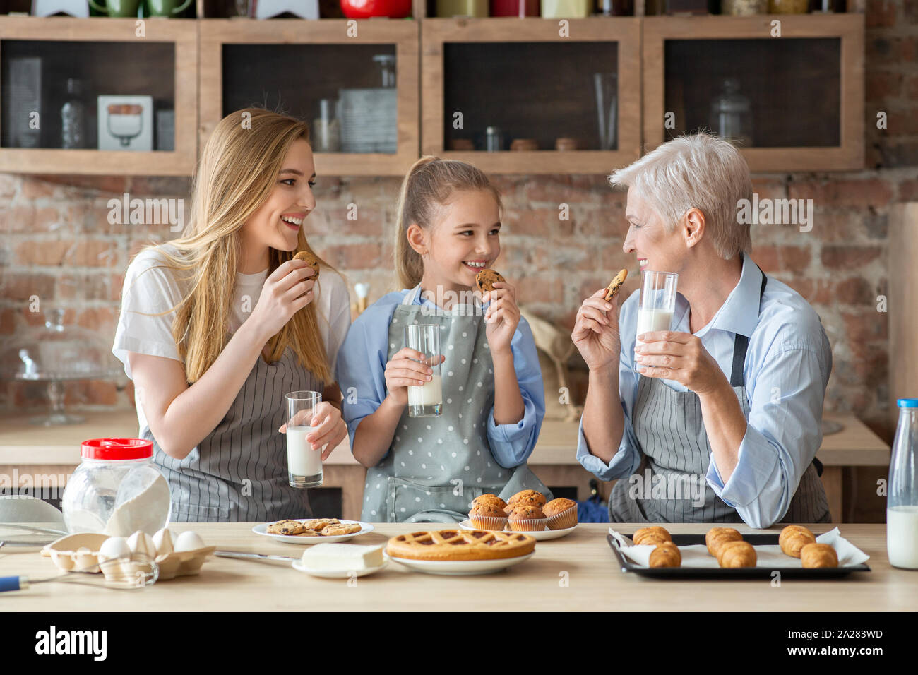 Famiglia femmina godendo di pasticceria fresca, latte alimentare Foto Stock