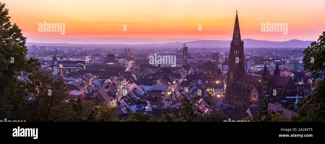 Germania, XXL panorama della skyline di Freiburg im Breisgau di notte dopo il tramonto con cielo rosso nel Magico crepuscolo da sopra Foto Stock