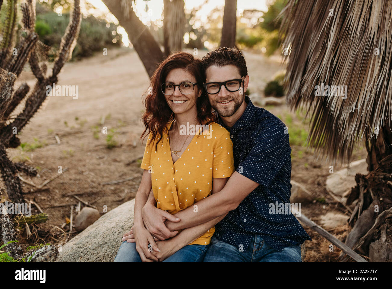 Metà adulto coppia sposata seduta sulla roccia di sorridere quando essi abbraccio vicino Foto Stock