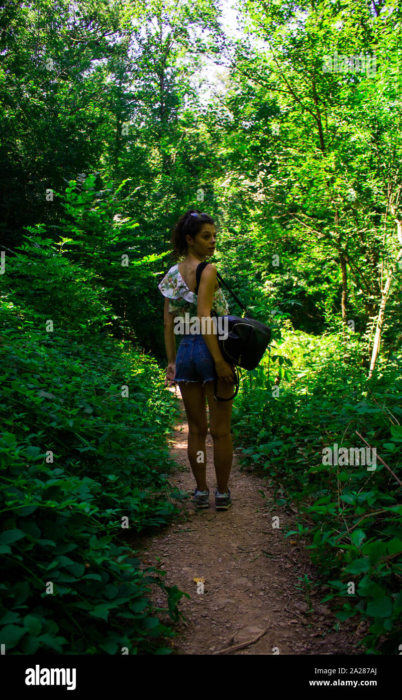 Giovane ragazza camminare lungo un sentiero circondato da vegetazione ed alberi Foto Stock