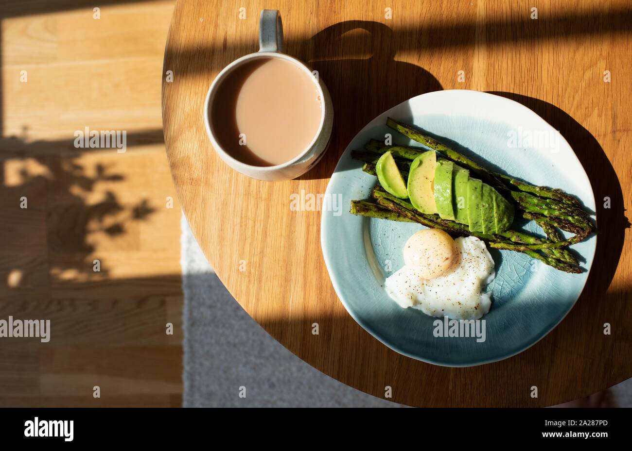 Uova, avocado, asparagi e una tazza di tè su un tavolo da caffè a casa Foto Stock