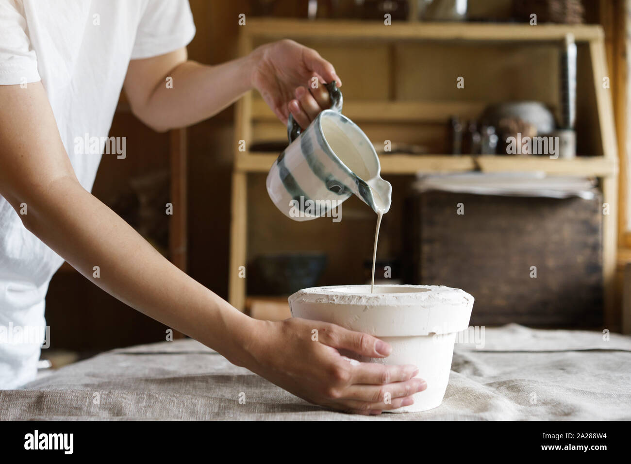 Mani femminili in ceramica versare la miscela in uno stampo. Foto Stock