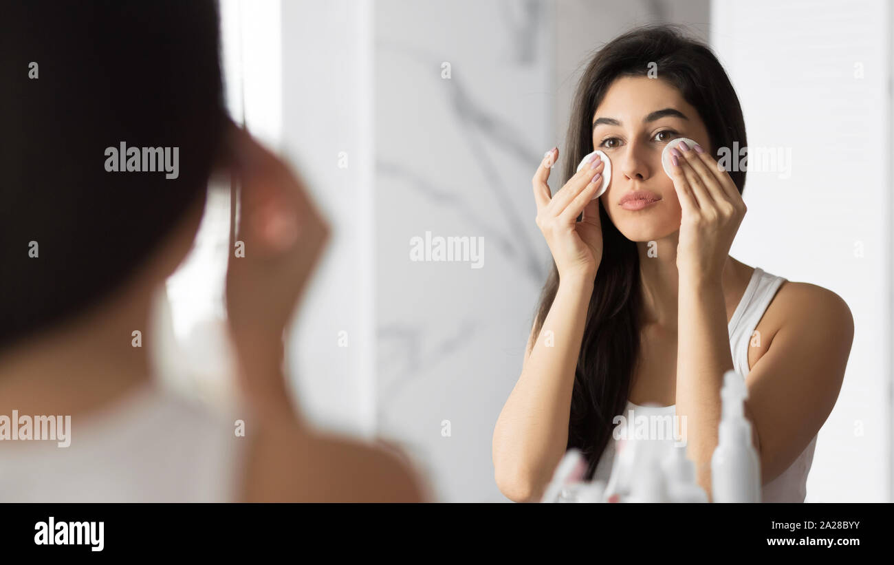 Ragazza Pulizia viso con tamponi di cotone nella stanza da bagno Foto Stock