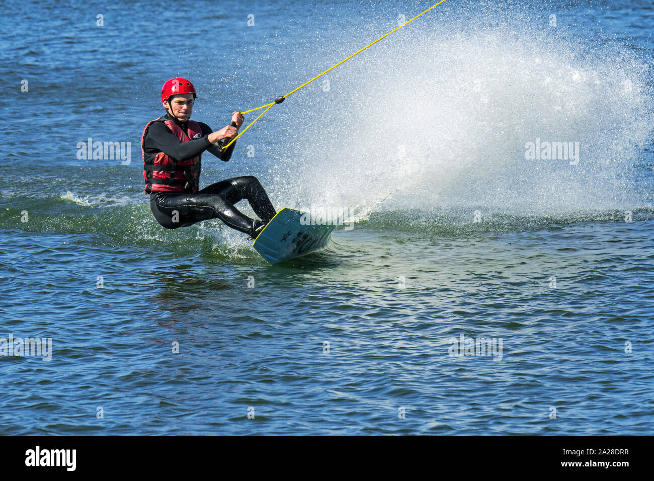 Wakeboarder / rider equitazione wakeboard trainato da elettricamente azionato da cavo a cavo corso di sci / wakeboard park Foto Stock