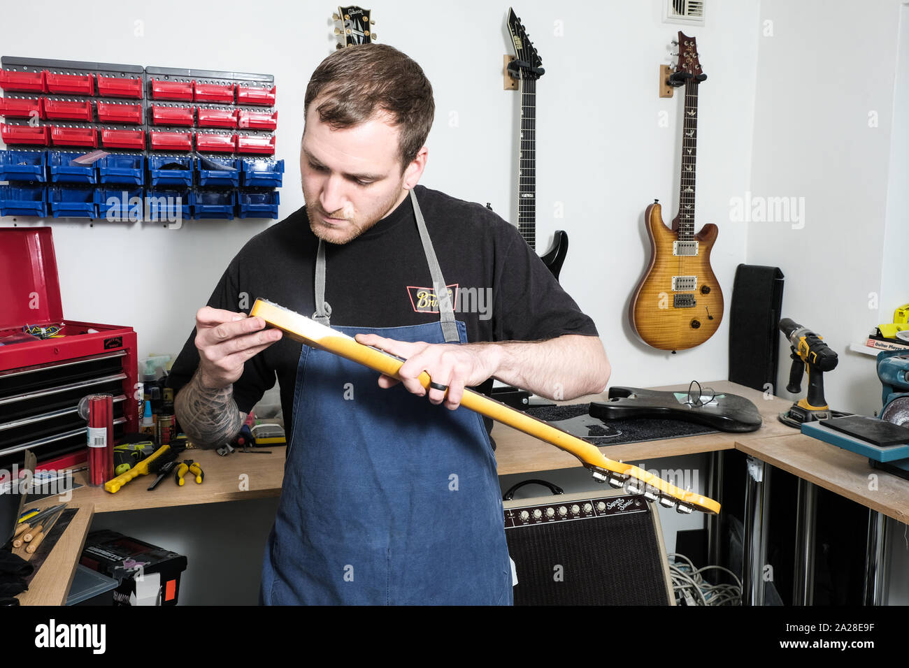 Una chitarra tecnico che sta lavorando sul fret board di una stratocaster chitarra. Lui è il controllo della fret board che si è staccata dalla chitarra Foto Stock