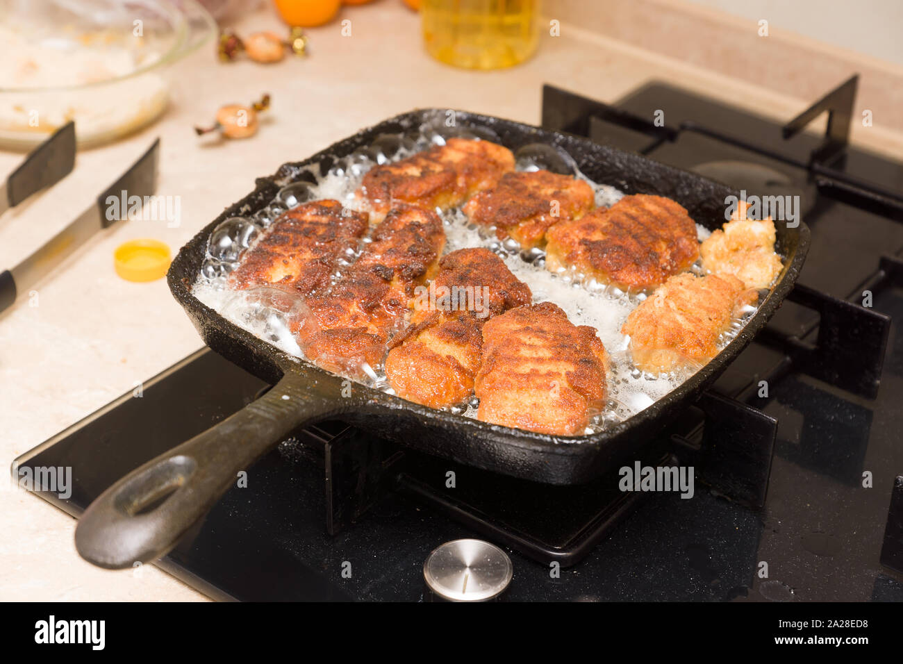 Pepite di cottura da freschi a base di carne di pollo su un caldo cast-padella di ferro Foto Stock