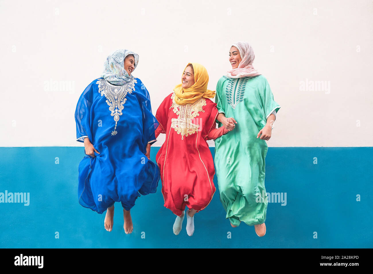 Felici le donne musulmane jumping insieme all'aperto - Arabian teen ragazze divertimento in città - Concetto di persone,costume, cultura e religione Foto Stock