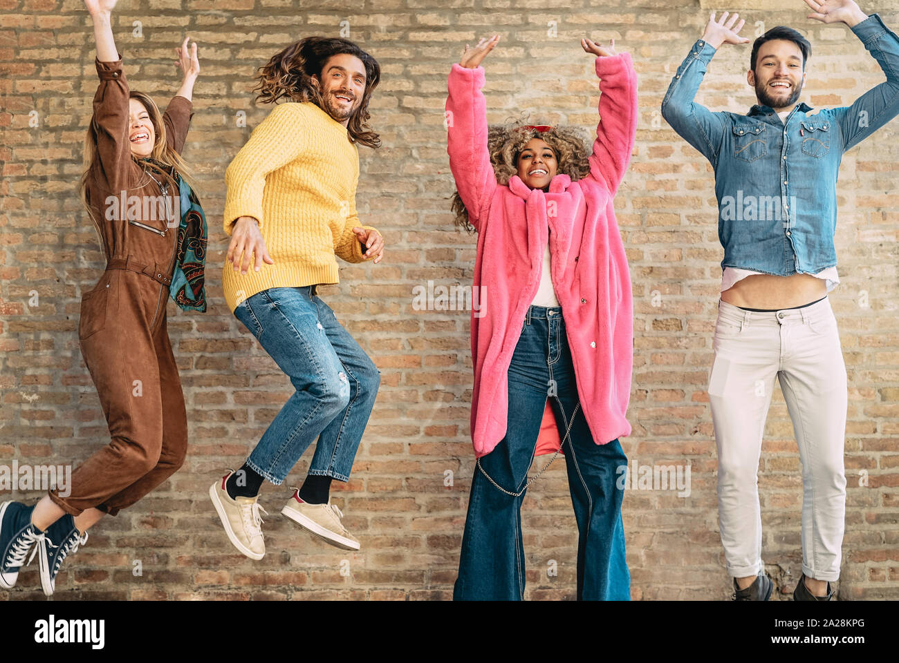 Happy amici jumping insieme outdoor - la millenaria giovani divertirsi ballare e festeggiare al di fuori Foto Stock