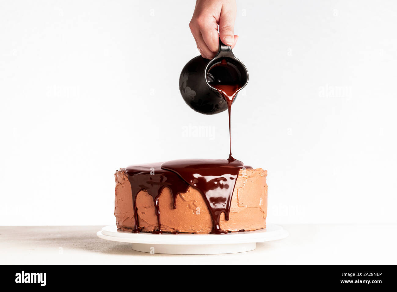 Vetri torta al cioccolato con il cioccolato fuso. Donna di cioccolato colata sulla torta. In casa di cacao torta stratificata. Torta di compleanno e gocce di cioccolato. Foto Stock