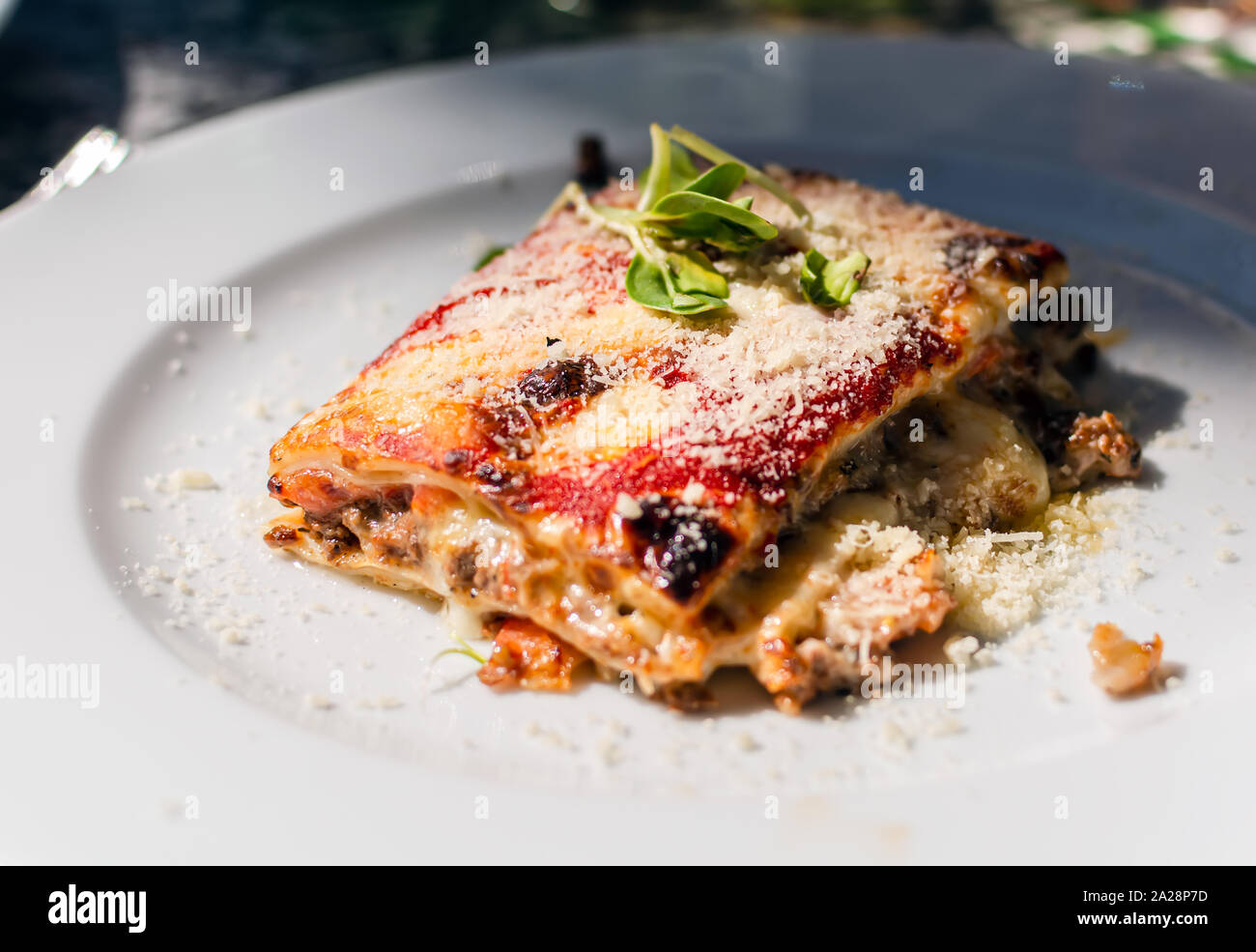 Lasagne con carne di manzo, i pomodori e le melanzane, in polvere con la mozzarella. Il ristorante serve. Lasagne sulla piastra bianca. Foto Stock