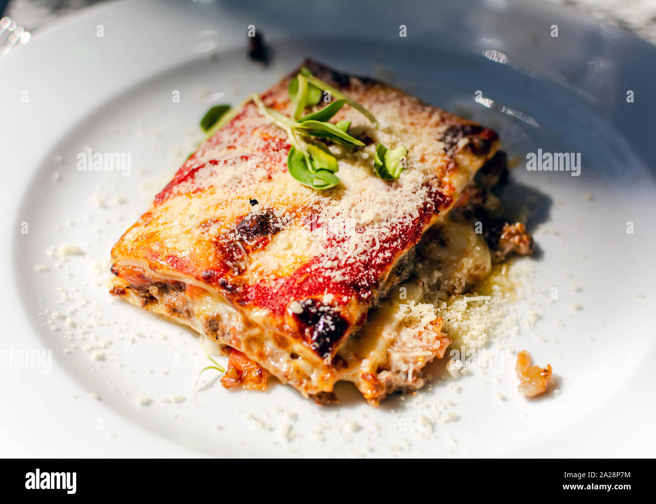Lasagne con carne di manzo, i pomodori e le melanzane, in polvere con la mozzarella. Il ristorante serve. Lasagne sulla piastra bianca. Foto Stock