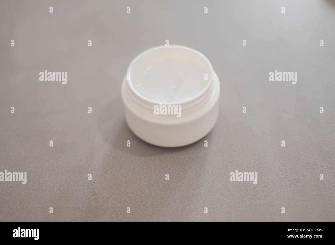 Una crema di bellezza in un contenitore in plastica su sfondo grigio Foto Stock