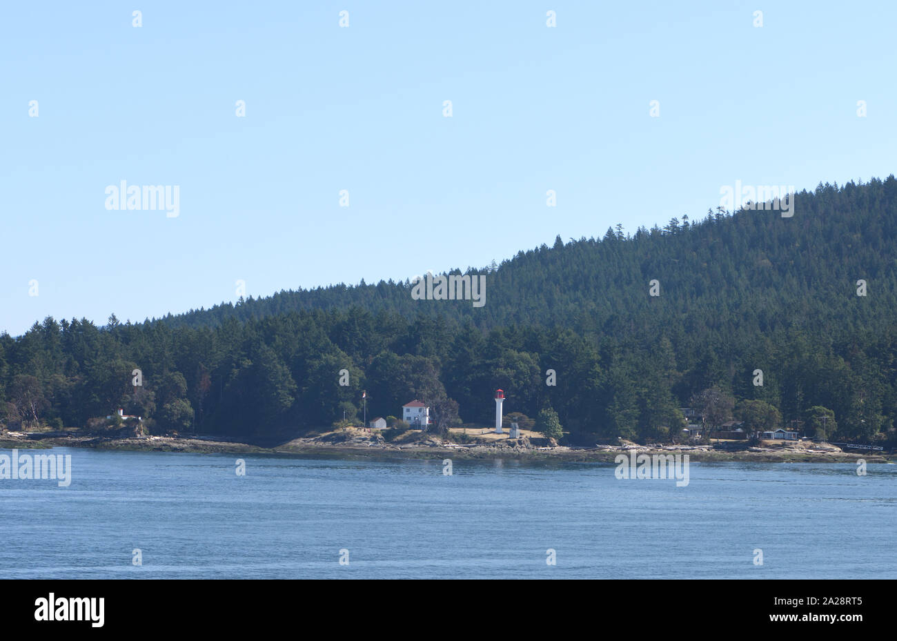 Isole coperte di conifere e promontori con barche e luci viste dal traghetto da Vancouver a Victoria. Vancouver, British Columbia, Canada. Foto Stock