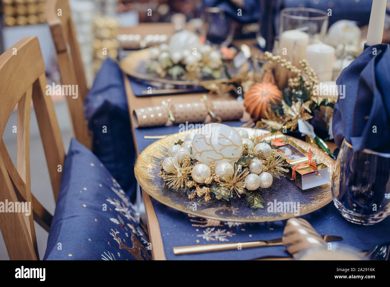 Christmastime impostazione tabella festosa stoviglie decorate con dettagli e palle bianche in blu e i colori dorati. Navy Blue Biancheria da tavola e oro Cutler Foto Stock