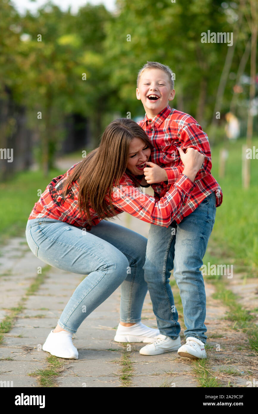 Madre e figlio, su un percorso nel parco, indulgere e ridere mentre si cammina. Foto Stock