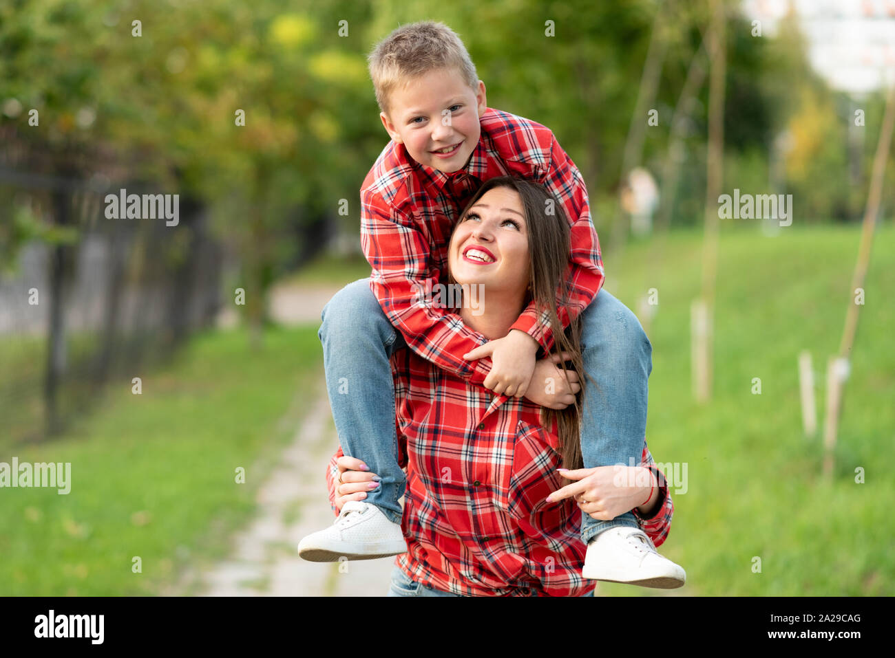 Mom ridevano allegramente porta un figlio sulle sue spalle. Foto Stock