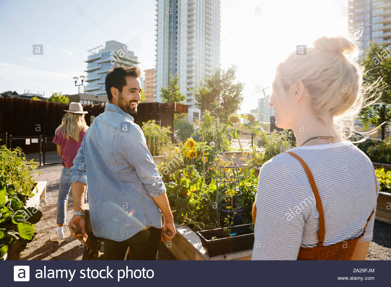 Felice coppia giovane nella soleggiata, urban comunità giardino Foto Stock