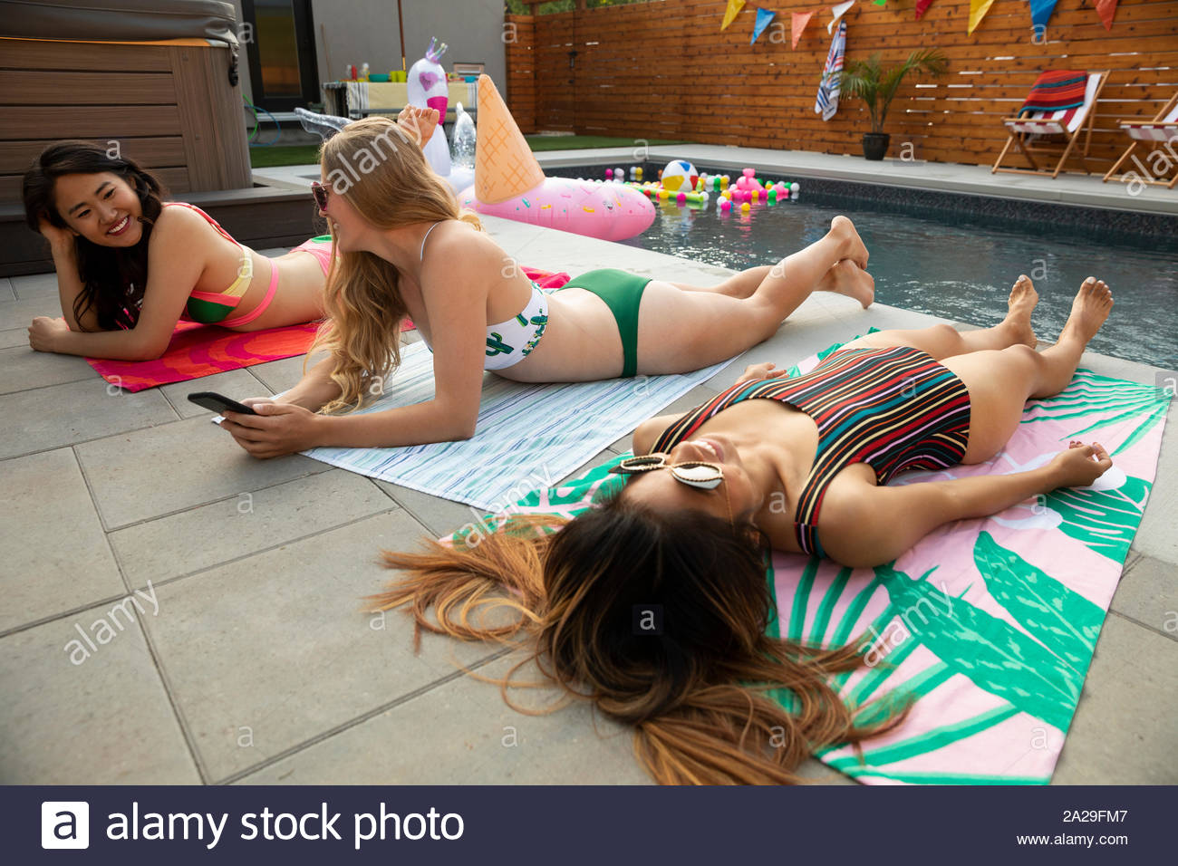 Spensierato di donne giovani amici appendere fuori, a prendere il sole a bordo piscina estiva Foto Stock