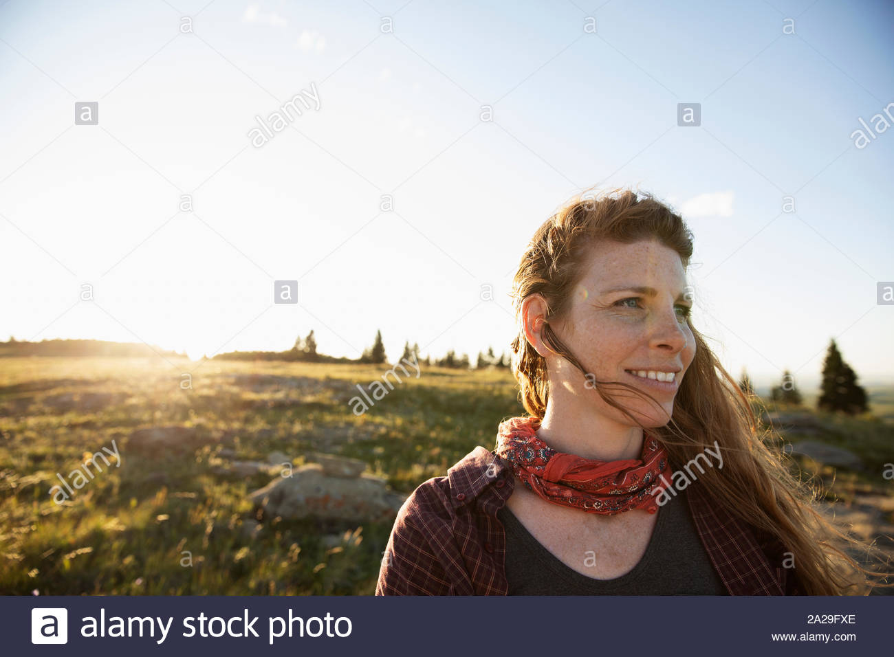 Donna sorridente con capelli spazzate dal vento su escursione rurale Foto Stock