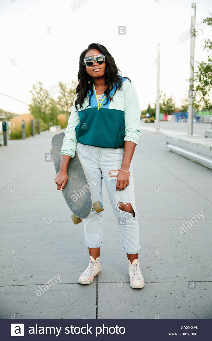 Ritratto fiduciosi, fresco giovane donna con lo skateboard Foto Stock