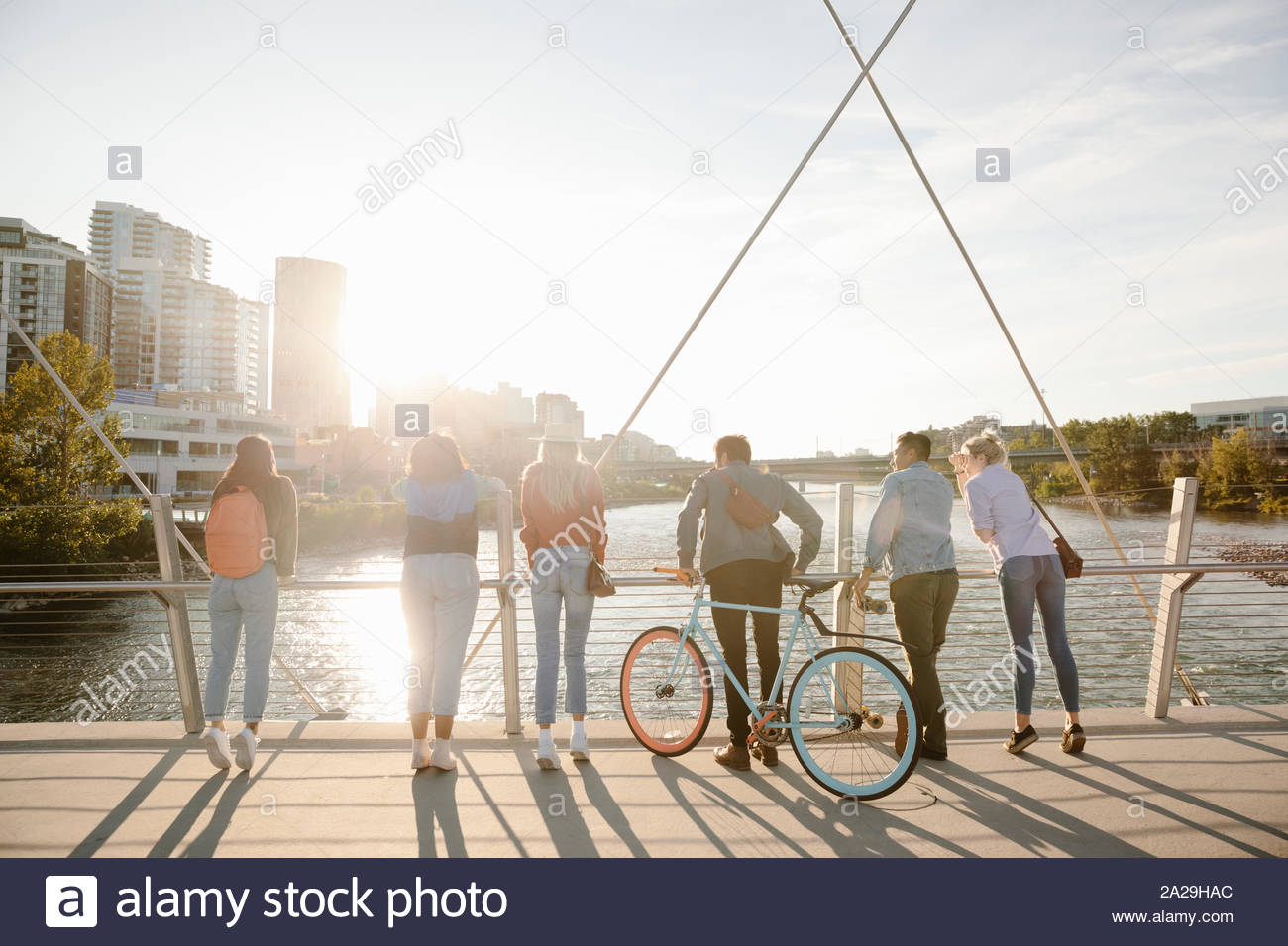 Giovani amici adulti guardando il fiume dalla soleggiata, ponte urbano Foto Stock